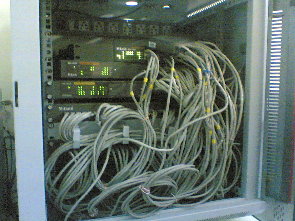 A disorganized network switch rack with tangled cables